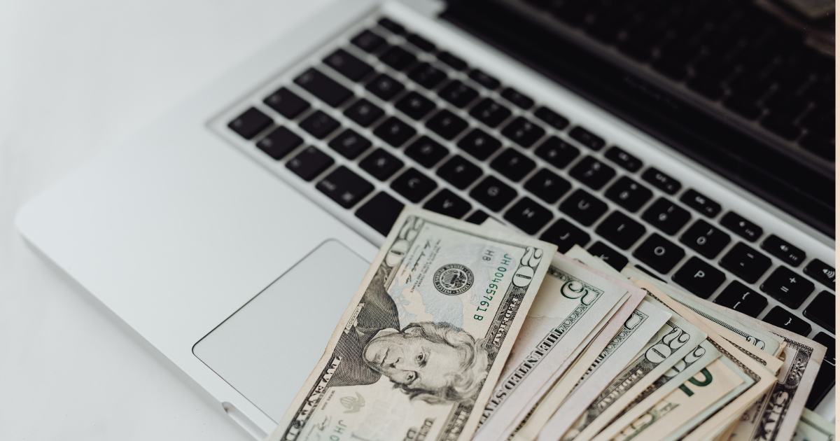 Notebook com notas de dinheiro sobre o teclado para ilustrar o custo de criação de sites profissionais